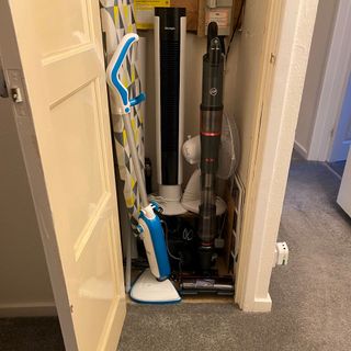 Hoover HFX cordless vacuum in cleaning cupboard