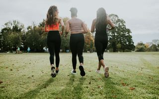 Rear view of female joggers running through a park