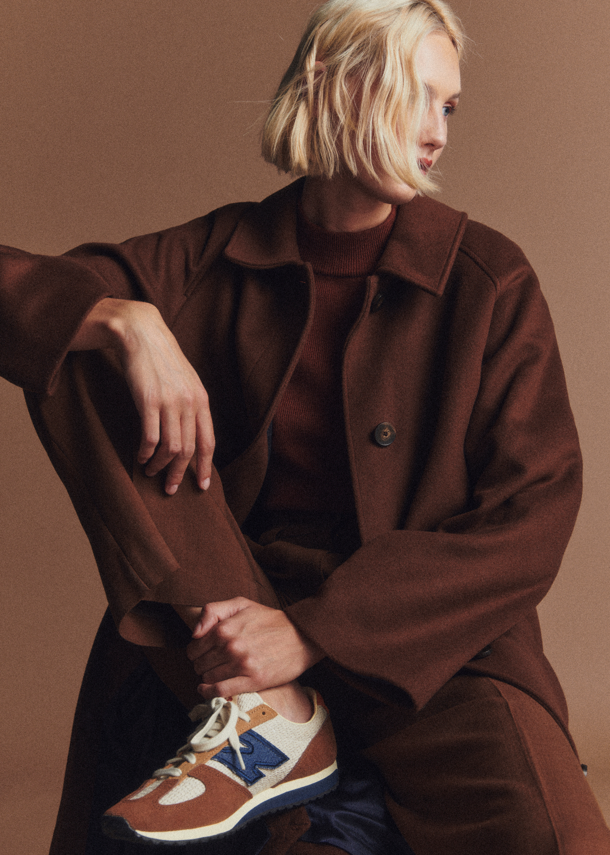 a model wearing a brown coat with S&amp;eacute;zane x New Balance sneakers