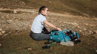 Writer Sam sat on the ground with her hiking bag during hiking trip laughing