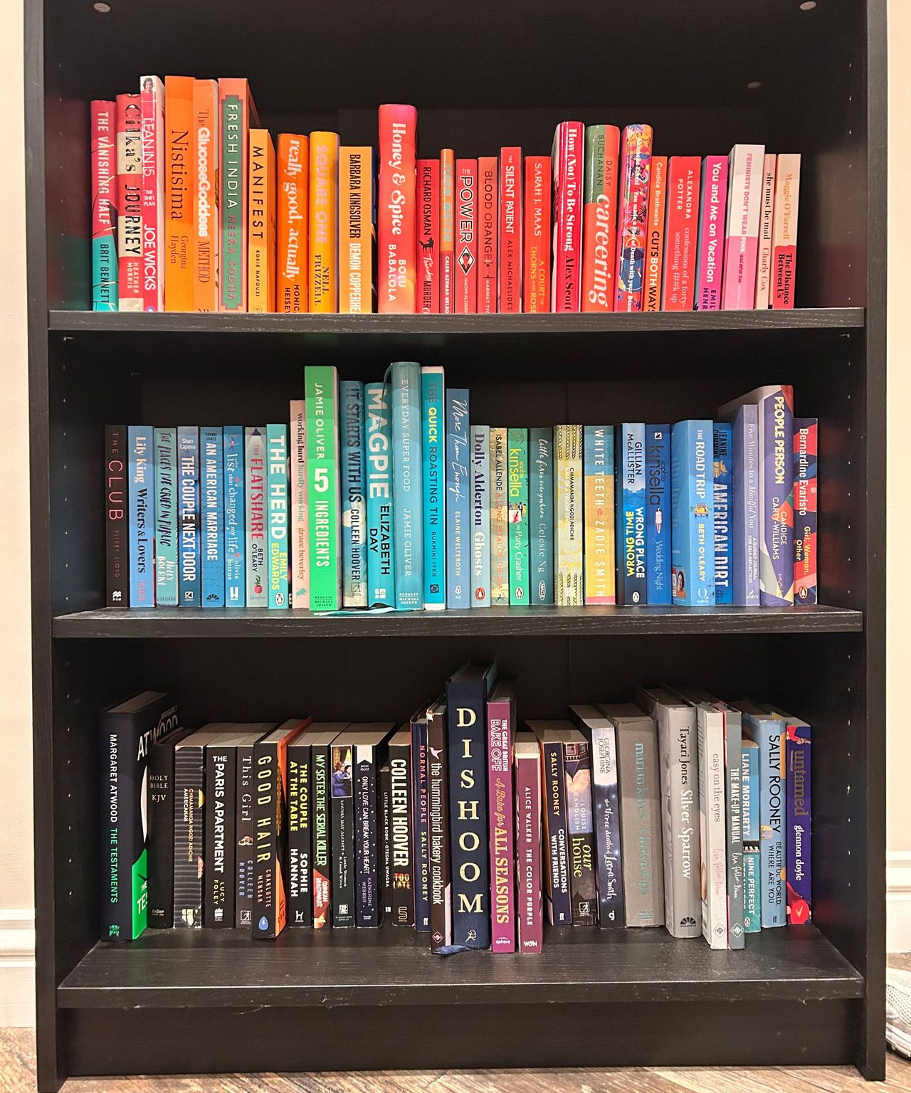 Black bookshelf with color-coordinated books stacked on it
