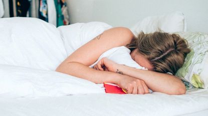 Young woman in bed, hiding her face into the duvet