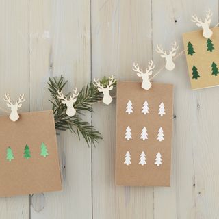 A stag shaped peg and twine Christmas card holder with light brown cards with metallic stag stickers