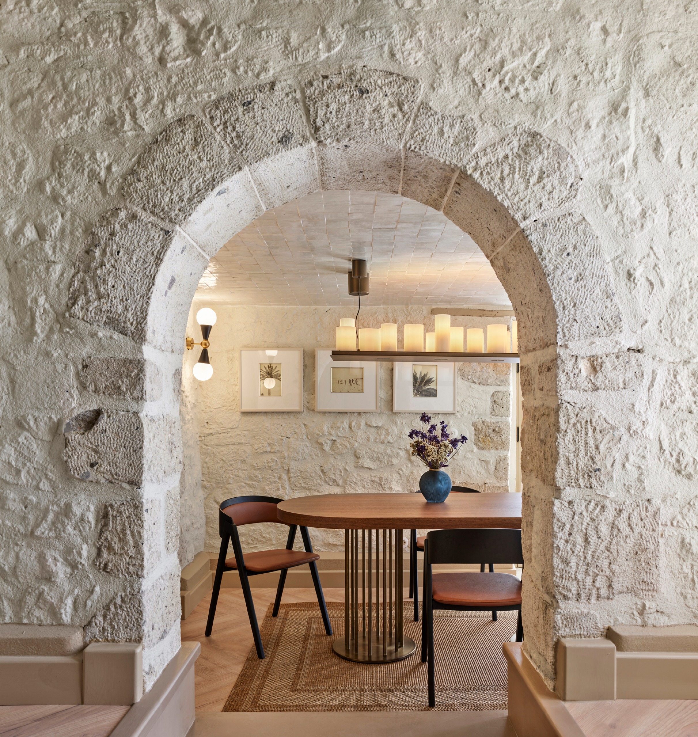 An old archway through to a modern dining table with layered lighting