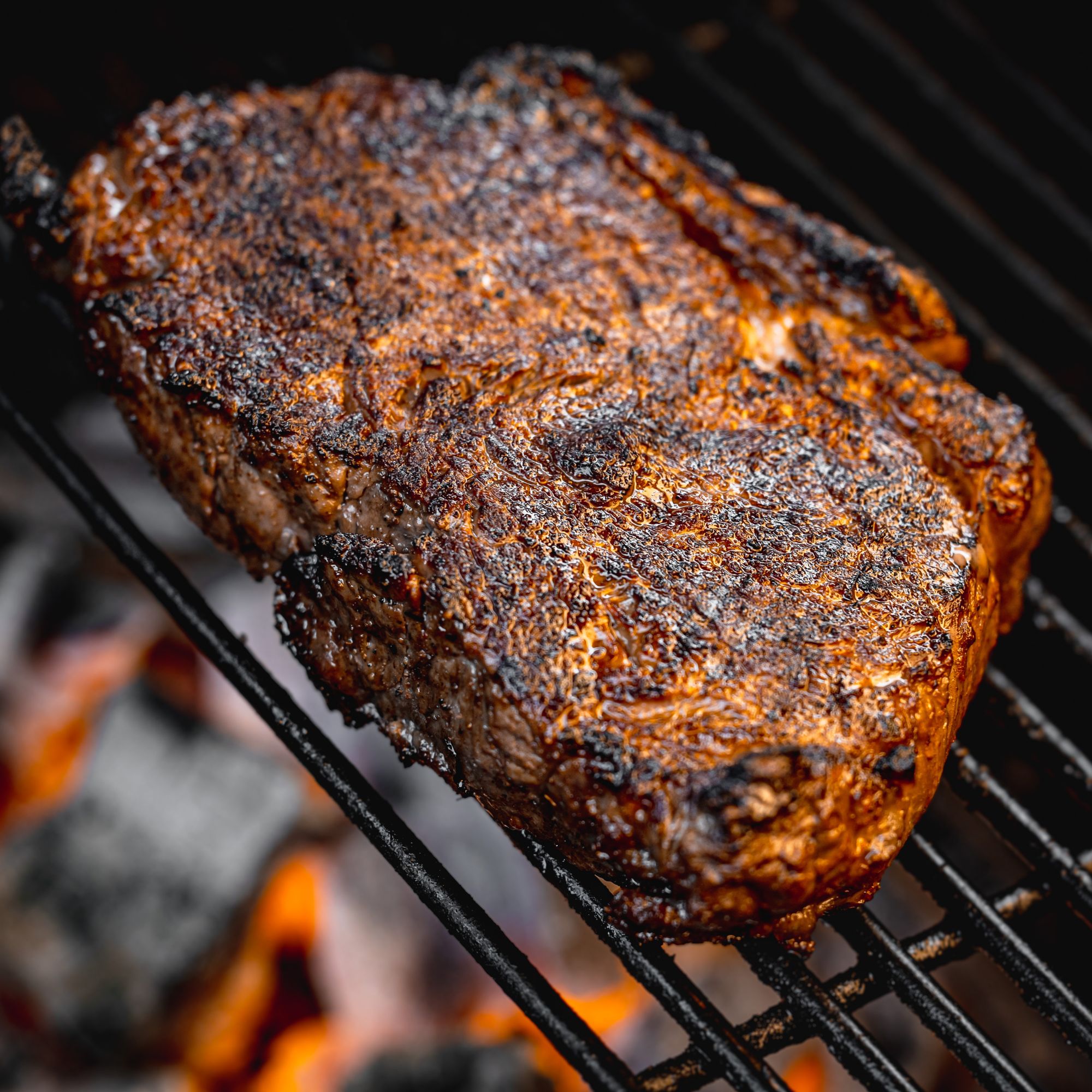 Meat cooking above charcoal burning in Kamado Joe BBQ