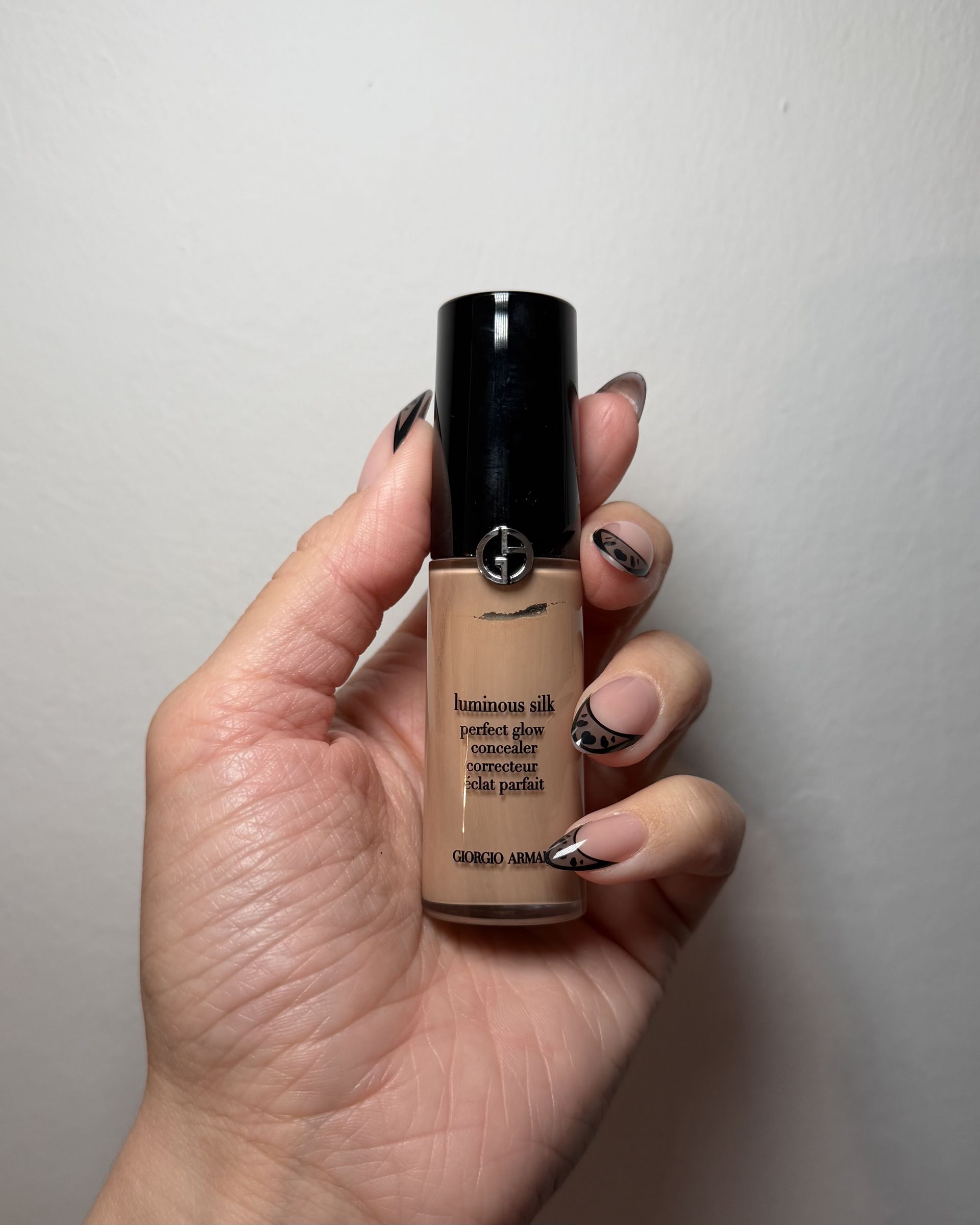 An image of Who What Wear associate beauty editor Alyssa Brascia wearing and holding the Armani Luminous Silk Hydrating Concealer.