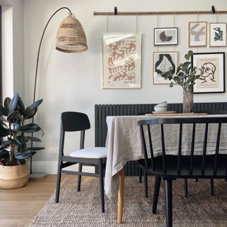 Dining area with black chairs and wooden table with tablecloth, galley wall on jute rug