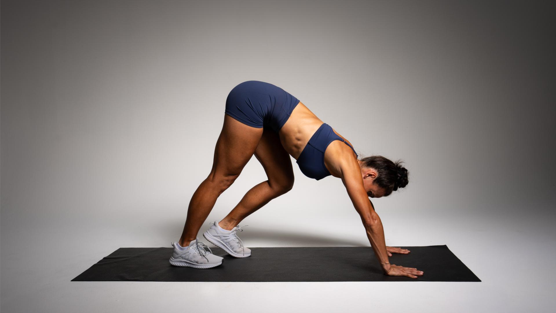 Woman in blue sportswear demonstrates a stretch against a studio background
