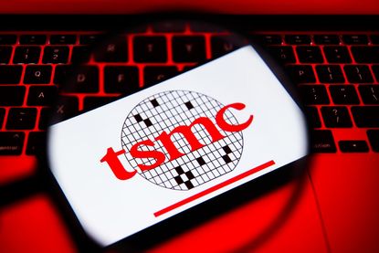 Taiwan Semiconductor logo on smartphone with computer keyboard in background under red lighting
