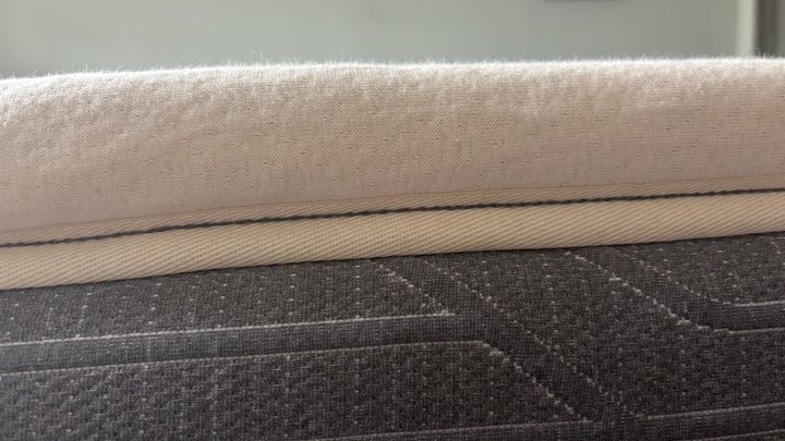 A close-up shot of the The Birch Plush Organic Mattress Topper's organic cotton cover on top of a memory foam bed.