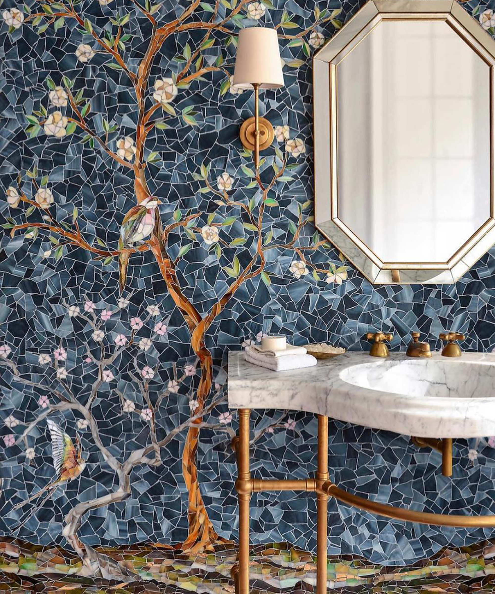 A small bathroom idea using a bespoke blue mosaic tile design depicting a flowering tree, with marble vanity and octagonal mirror