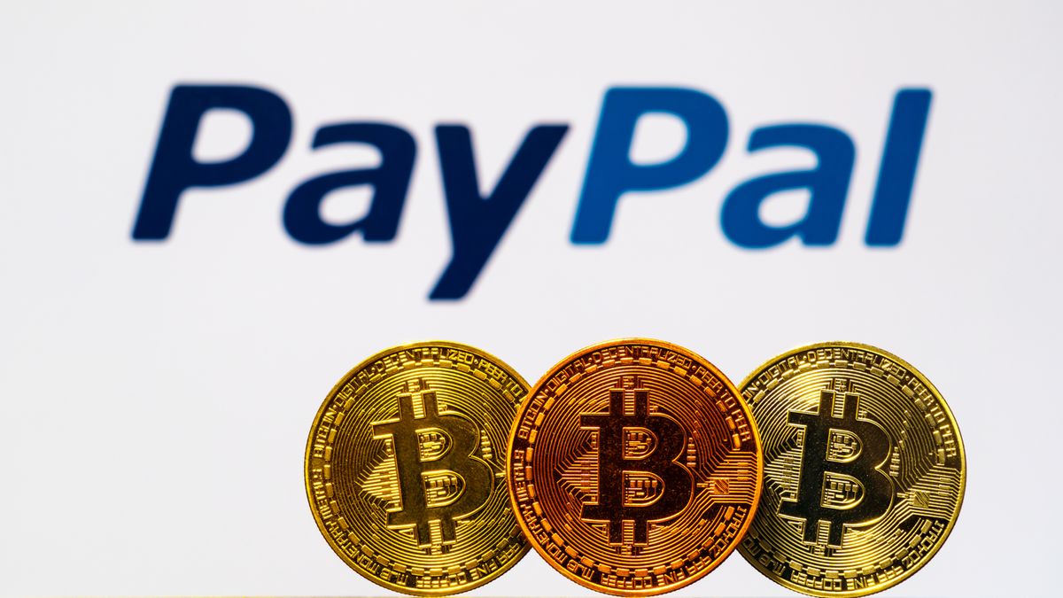 Three physical coins with the branded with the Bitcoin logo in front of the PayPal logo