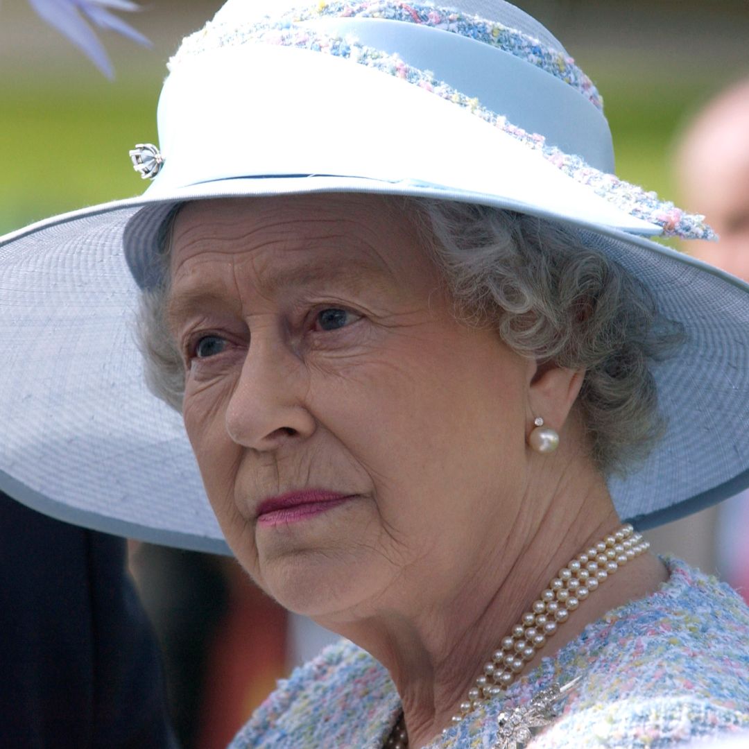 Queen Elizabeth wears a blue hat and a pearl necklace