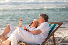 Retired couple drinking a cocktail on the beach.