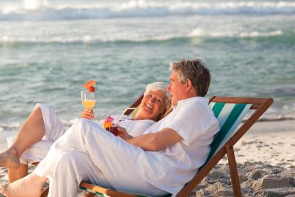 Retired couple drinking a cocktail on the beach.