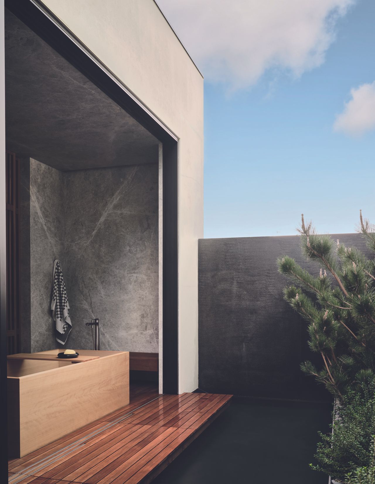 A zen bath tub overlooks the outdoor oasis for maximum relaxation, with natural materials blending into the surrounds