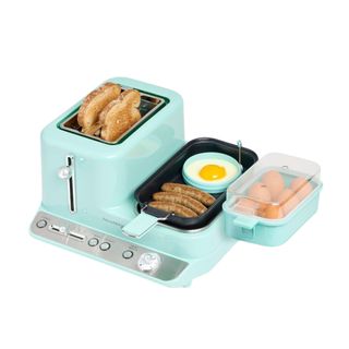 A light blue toaster breakfast station with two slices of toast, a black griddle pan with bacon and an egg, and a container with six boiled eggs in it