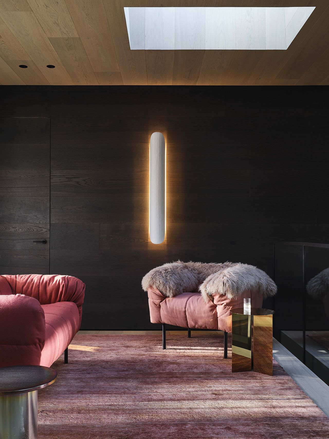 A sitting area beneath a skylight with pink-tinged furniture