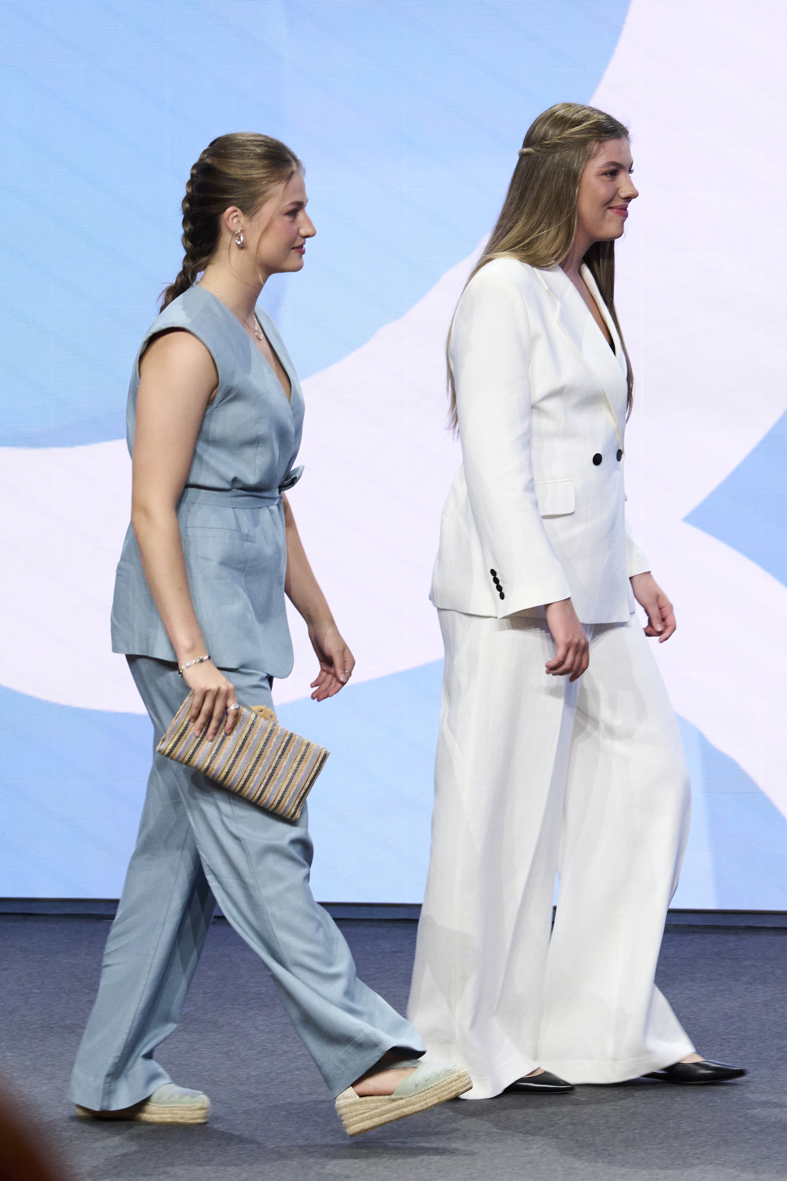 Princess Leonor and Princess Sofia wearing suits walking on a stage
