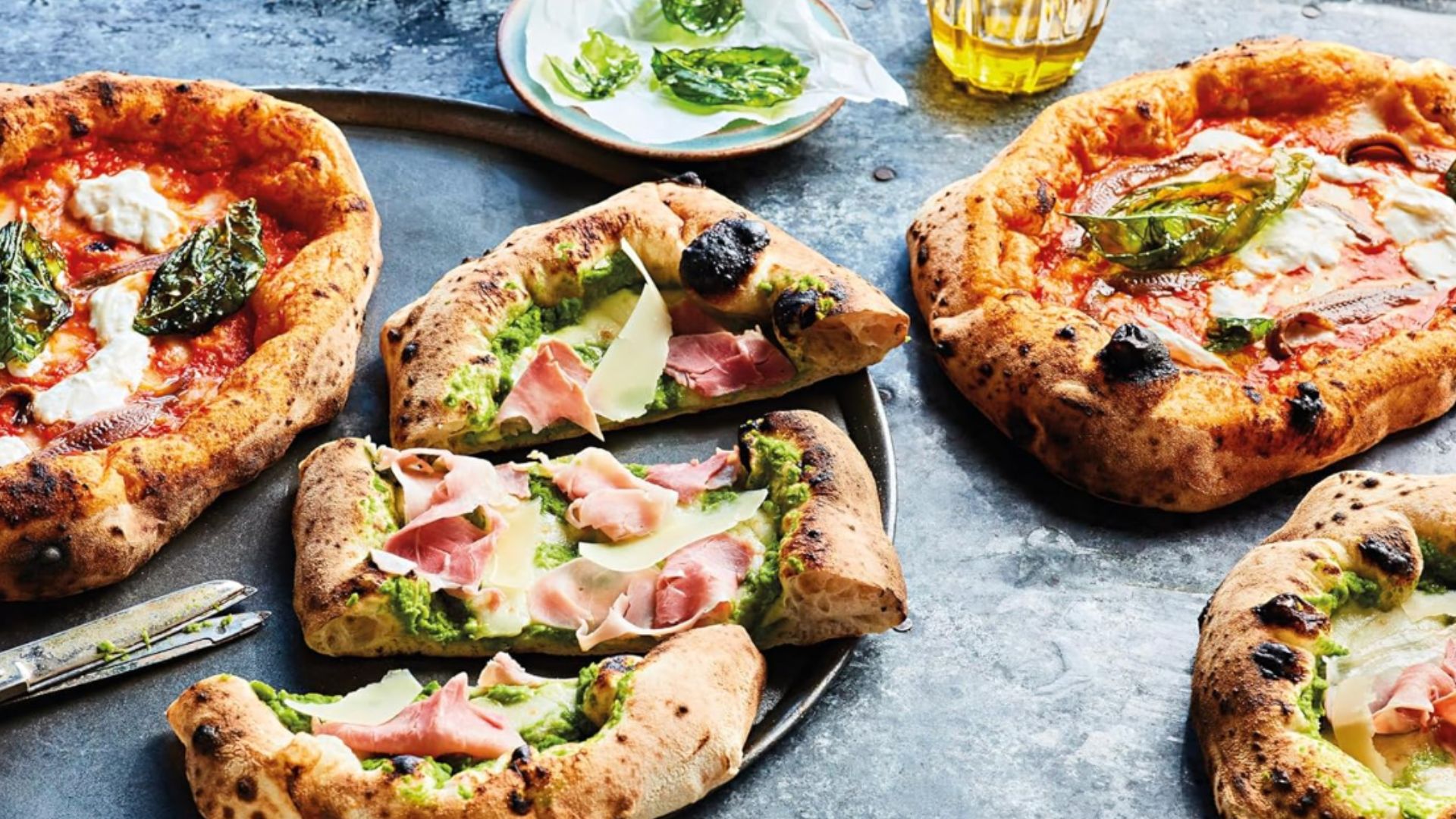 an image of three different pizzas laid out on a flour topped slate table
