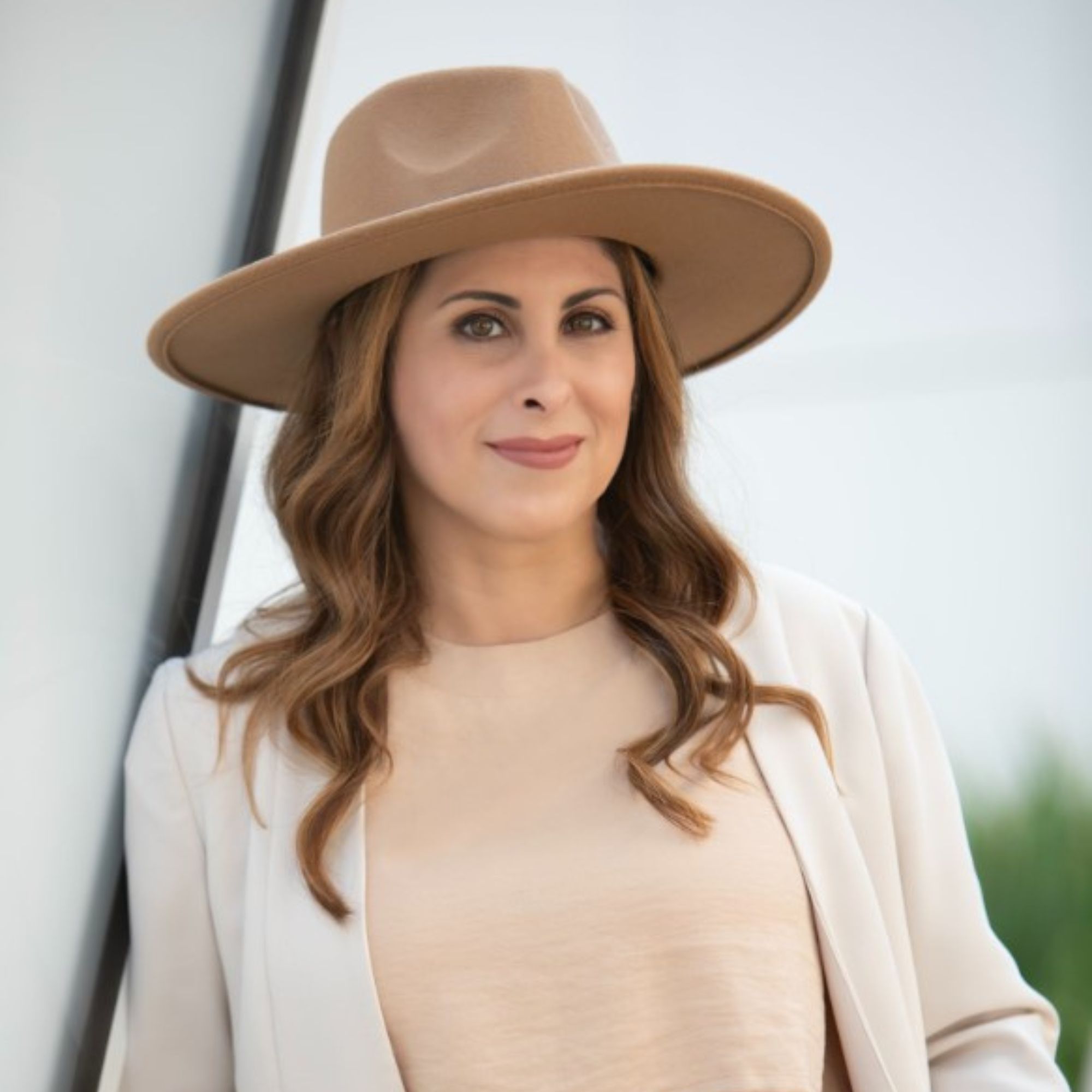A picture of Reya Duenas, a woman wearing a brown hat, a white cardigan, and beige shirt