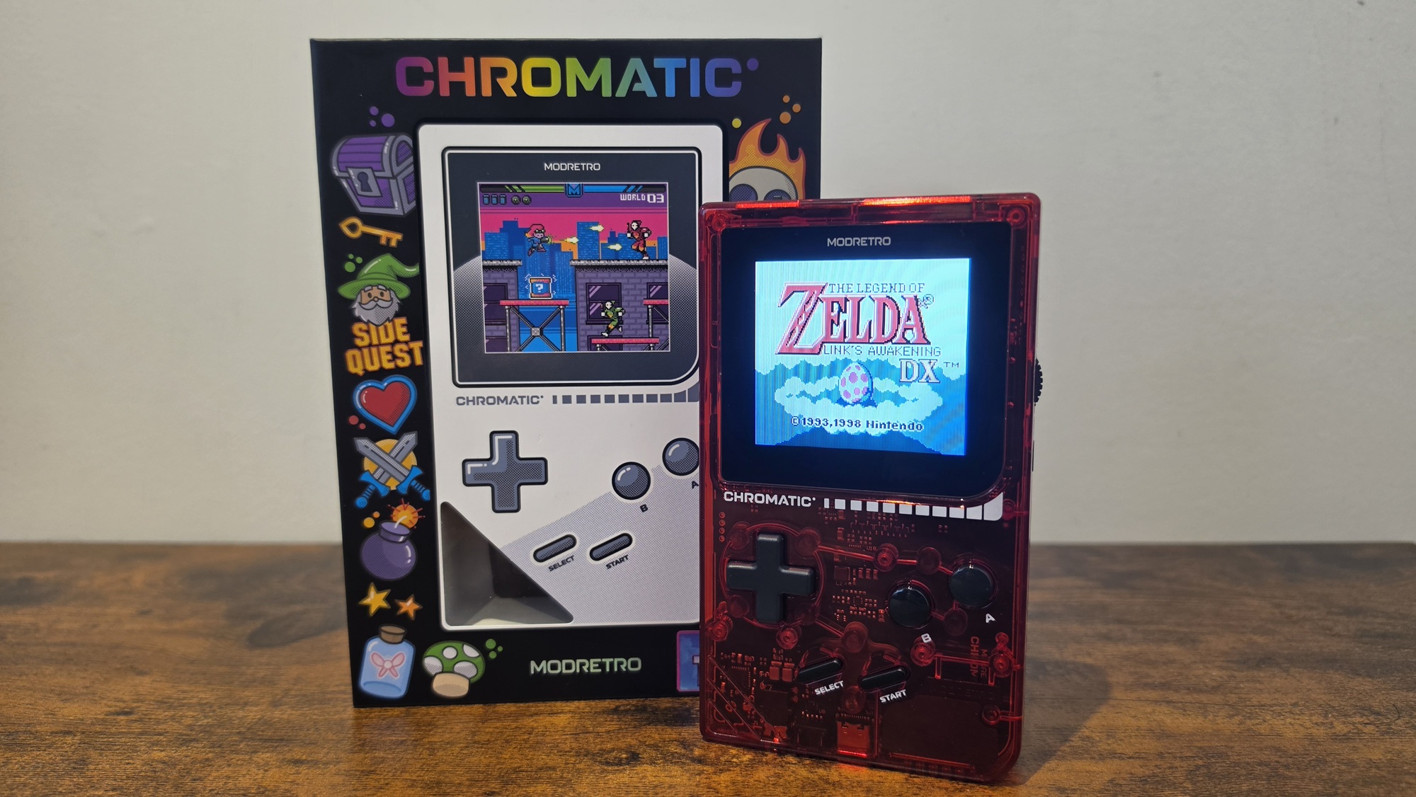 The ModRetro Chromatic Transparent in red showing the home screen of The Legend of Zelda Link's Awakening DX standing up next to the Chromatic box
