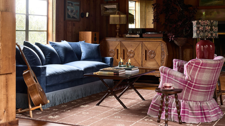 a cozy living room with a plaid skirted accent chair and a blue fringe sofa