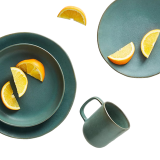 Anthropologie pasta bowls, mug, and sliced oranges with the dining ware in a shade of teal