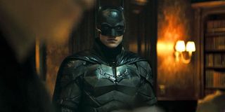 Batman (Robert Pattinson) stands at a crime scene in The Batman (2022)