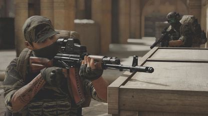 A soldier looks over the barrel of his rifle at an unseen target
