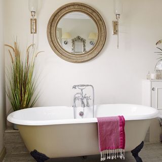 bathroom with bathtub and round mirror