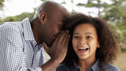 A dad tells his young daughter a secret.