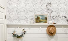 half wallpapered wall and half white shiplap with pegs and decorative foliage on shelf