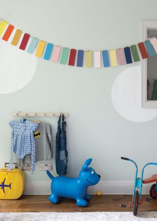 A child's playroom painted pale gray with large white dots and colorful bunting and toys.