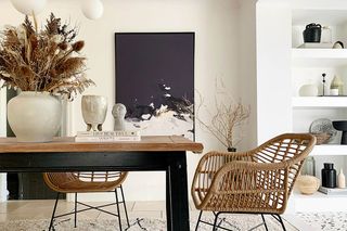 Black and white abstract art piece hung on the wall in dining room with wooden dining table and decorative elements