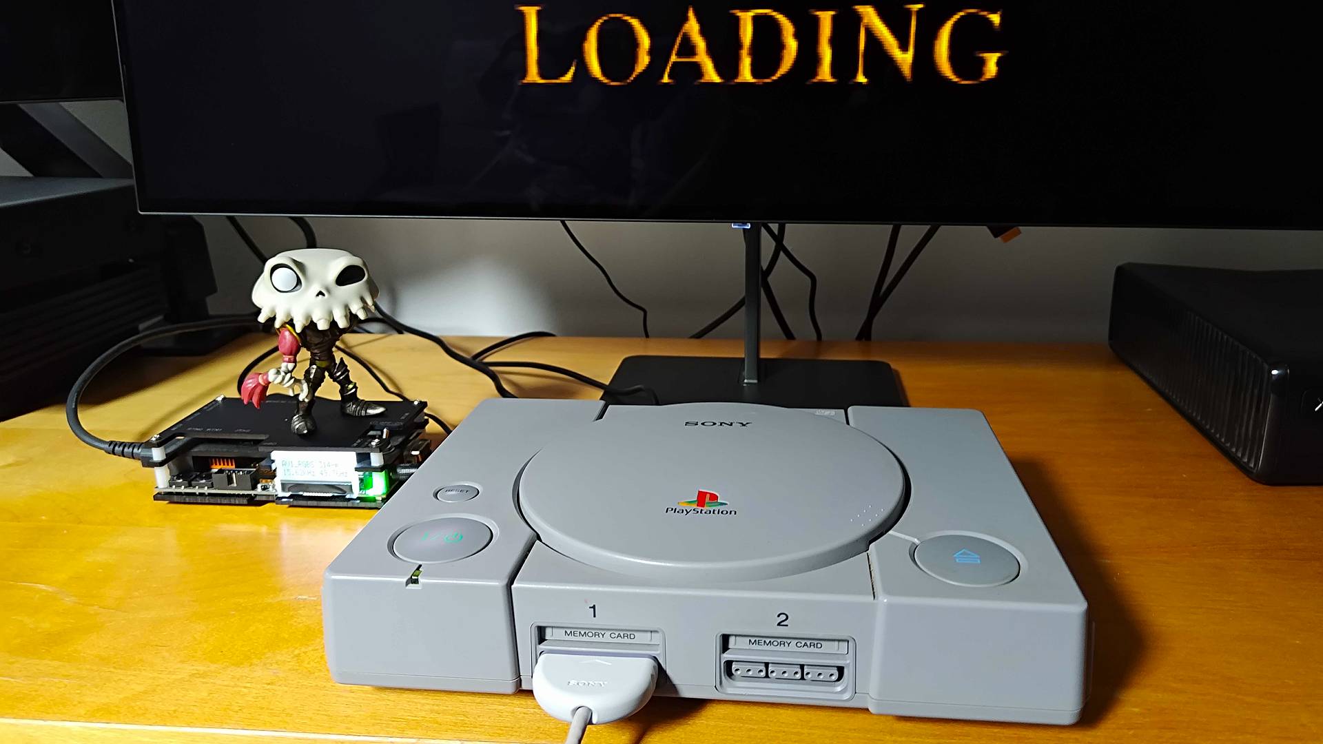 Original PlayStation console on unit next to OSSC upscaler with Sir Dan MediEvil figure on top.