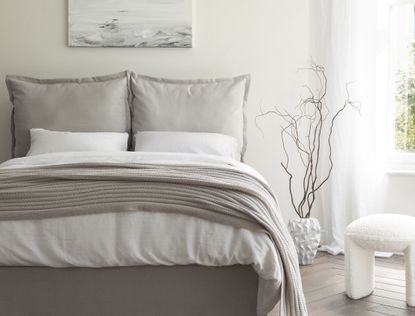 A neutral bedroom with a grey bed and a grey throw blanket