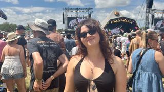 A Tom's Guide Sleep Features Editor smiling at Glastonbury Festival with the Pyramid Stage behind her