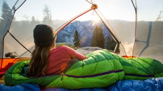 sleeping bag temperature: camper looking out at dawn
