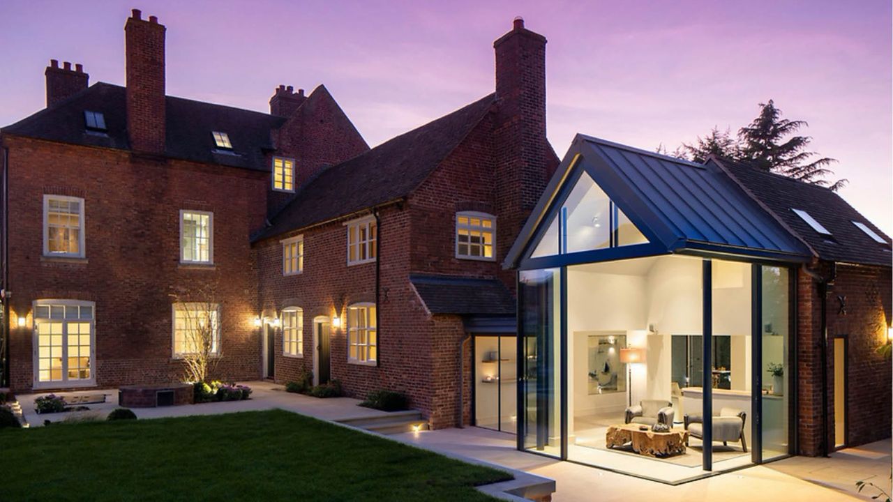 Large house exterior with lights on at dusk