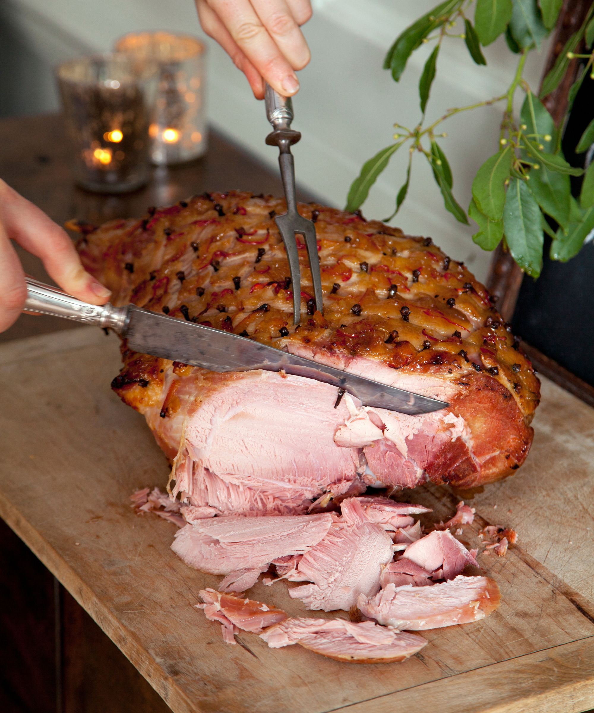 Someone cutting a Christmas ham on a wooden board