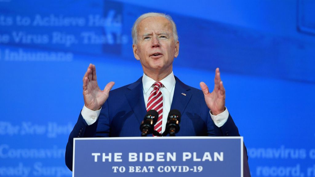 Biden stands at a podium with a sign on it that reads &quot;The Biden Plan to Beat COVID-19&quot;