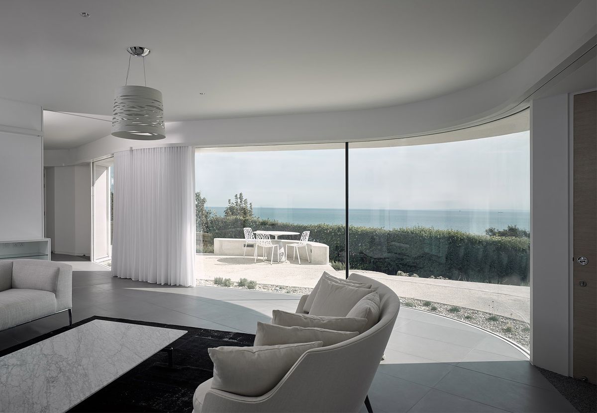 large living room with curved glazing and view to sea