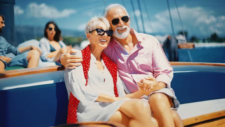 Senior couple enjoying sailing cruse on family summer vacation.