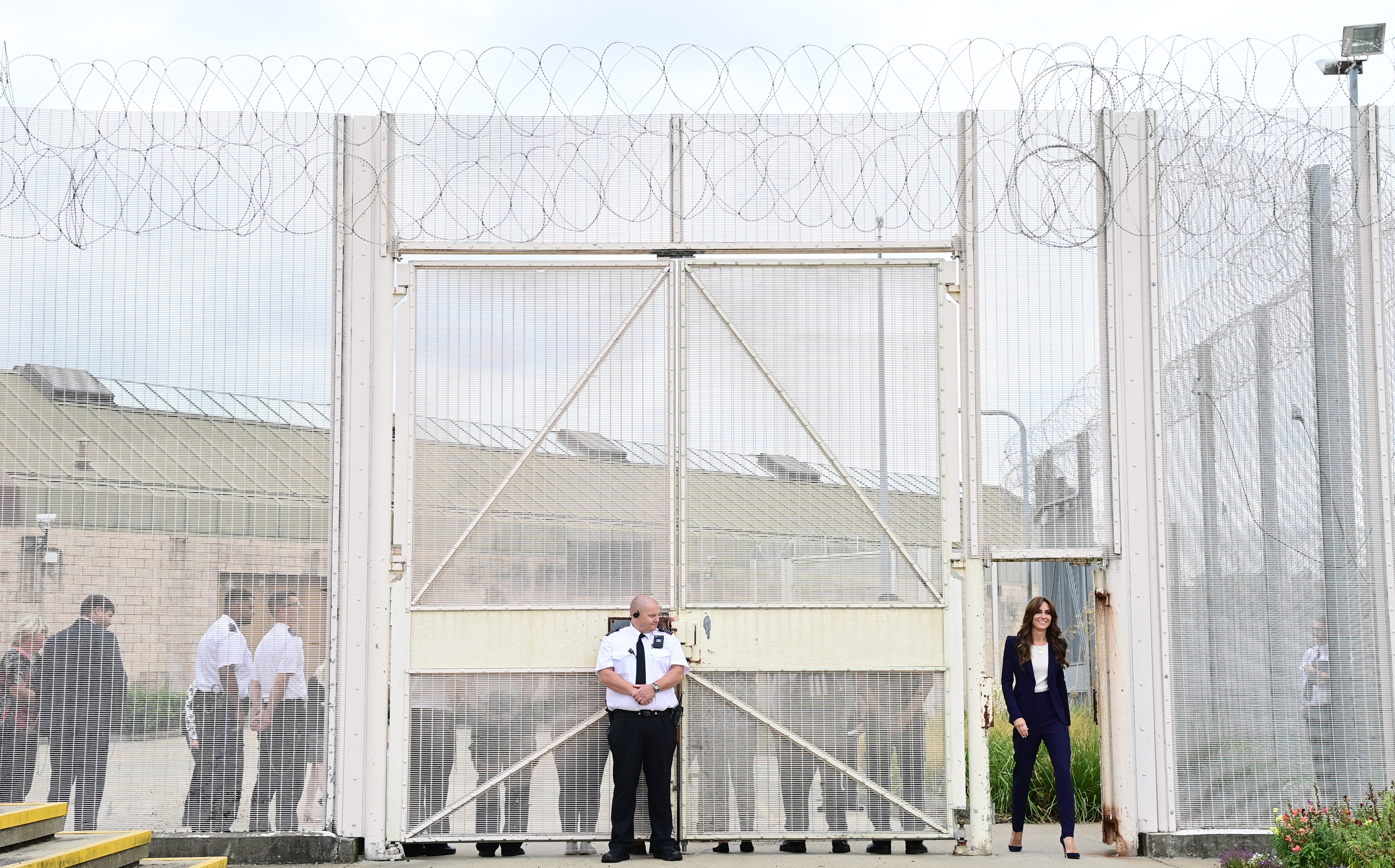 Kate Middleton walking through a prison gate in a blue suit
