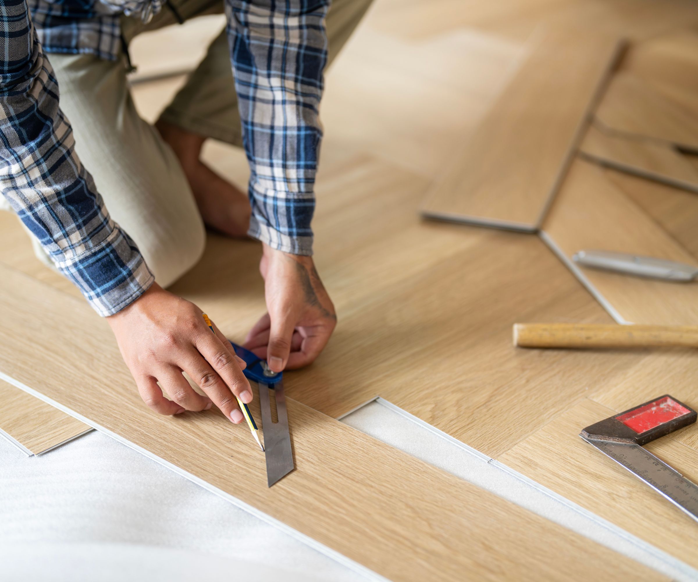 Worker installing laminated wooden floor indoors, closeup