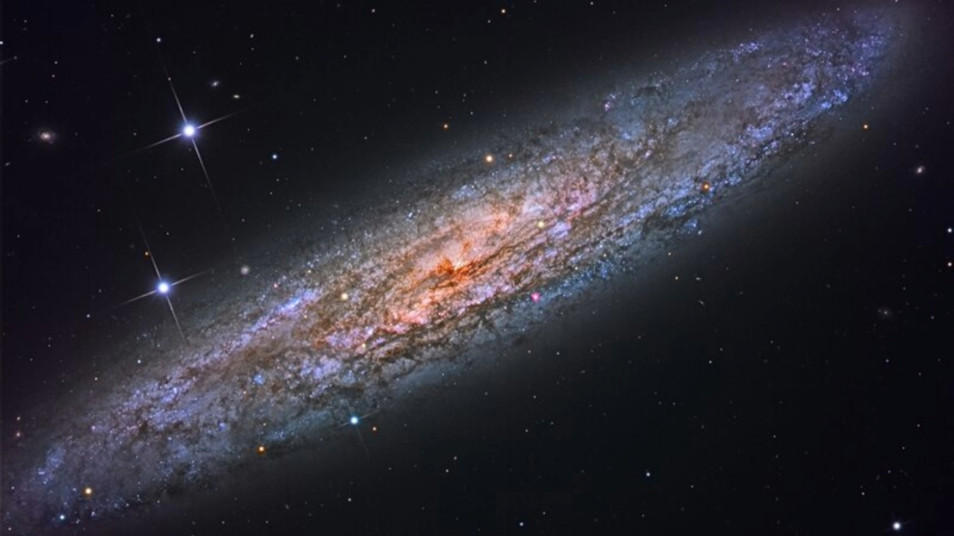A spiral galaxy is tilted to the left in outer space