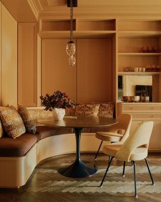 A yellow dining nook with a built-in, curved banquette