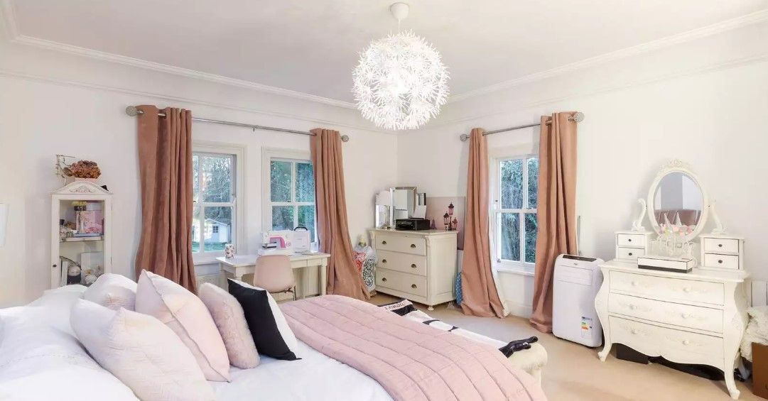 The bedroom has a pink covered bed and square framed windows