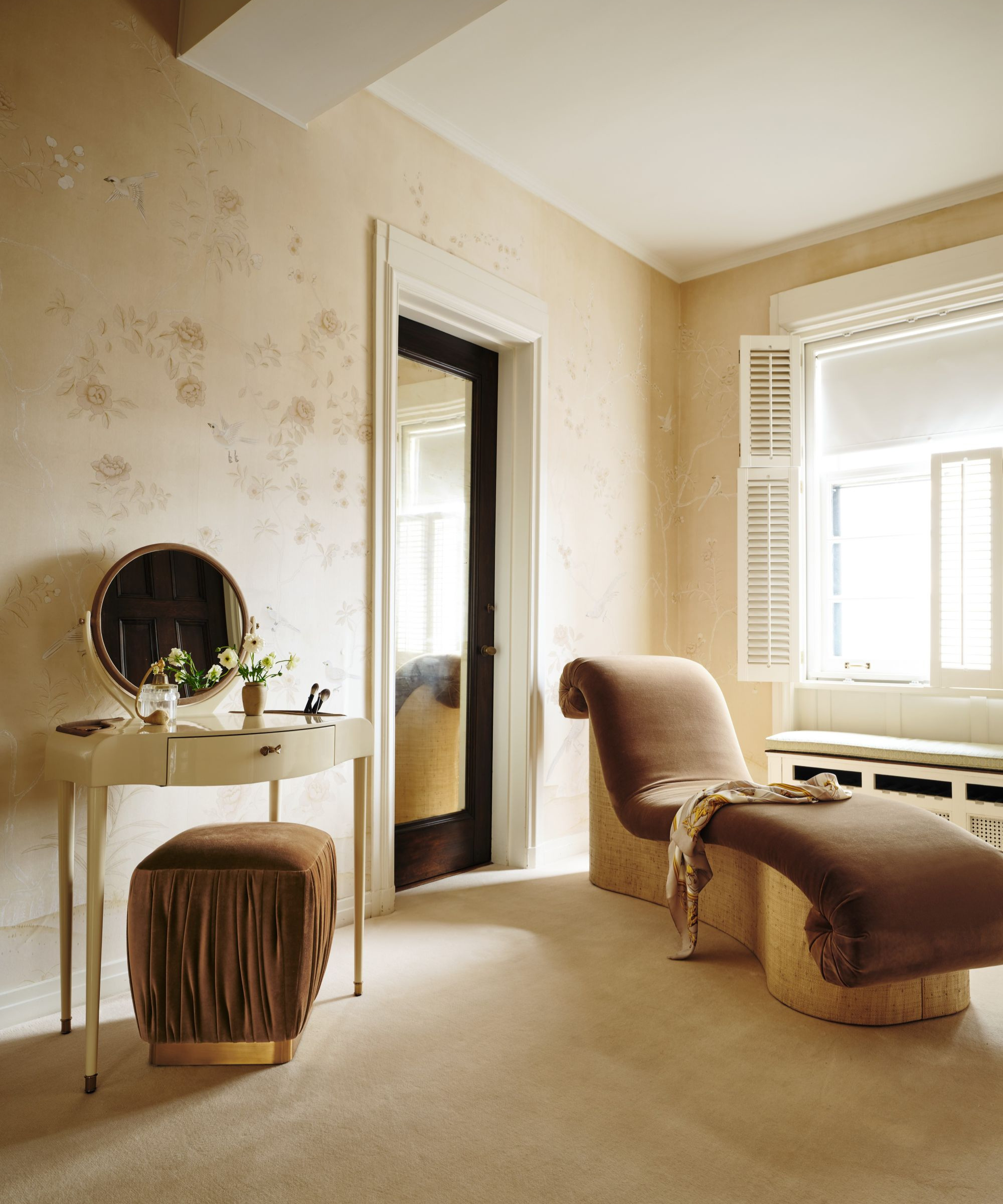 a dressing room with a chaise lounge chair and a small vanity table with an ottoman underneath